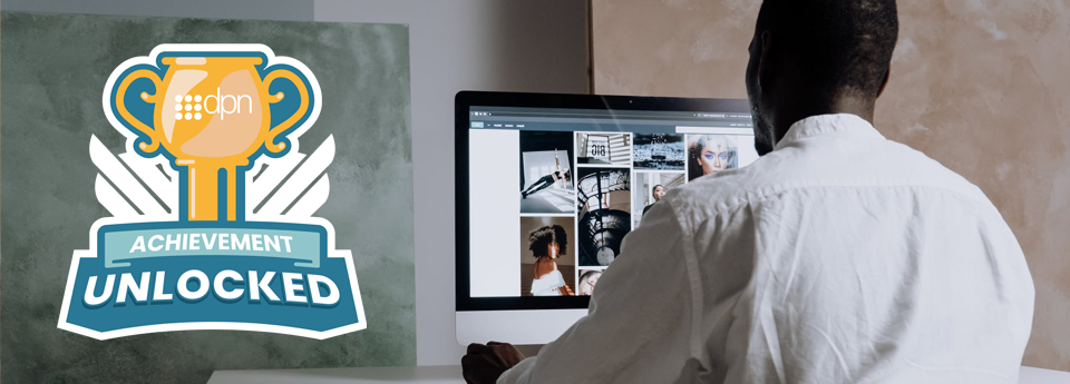 Stock Image Website Header with Achievement Unlocked logo on the left. Man using Mac PC on the right, browsing stock images.